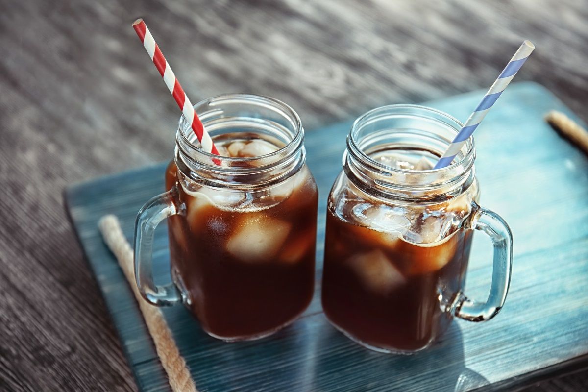 Mason jars with cold brew coffee on wooden tray