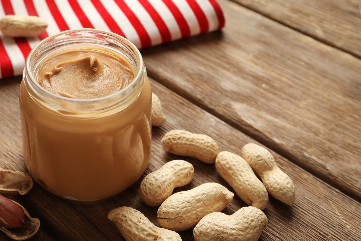 Jar with creamy peanut butter on table