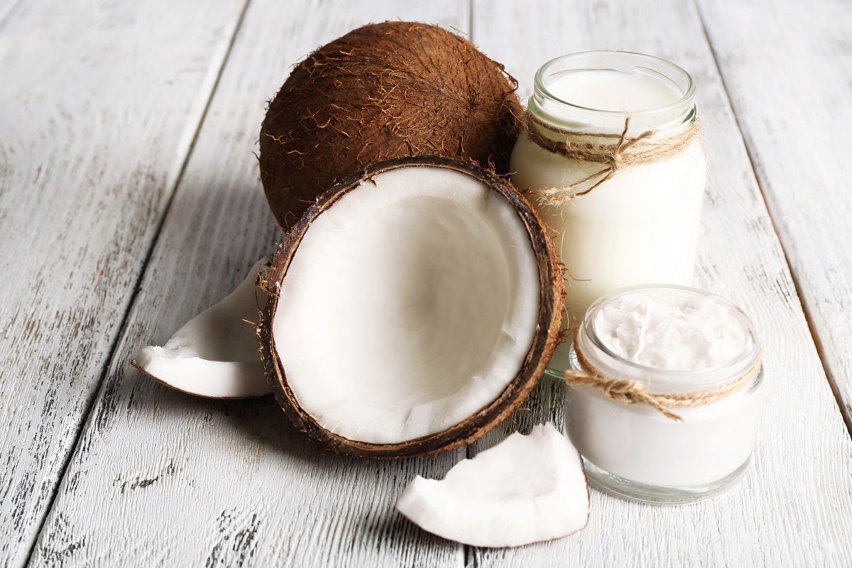 Fresh coconut oil in glassware on color wooden table background