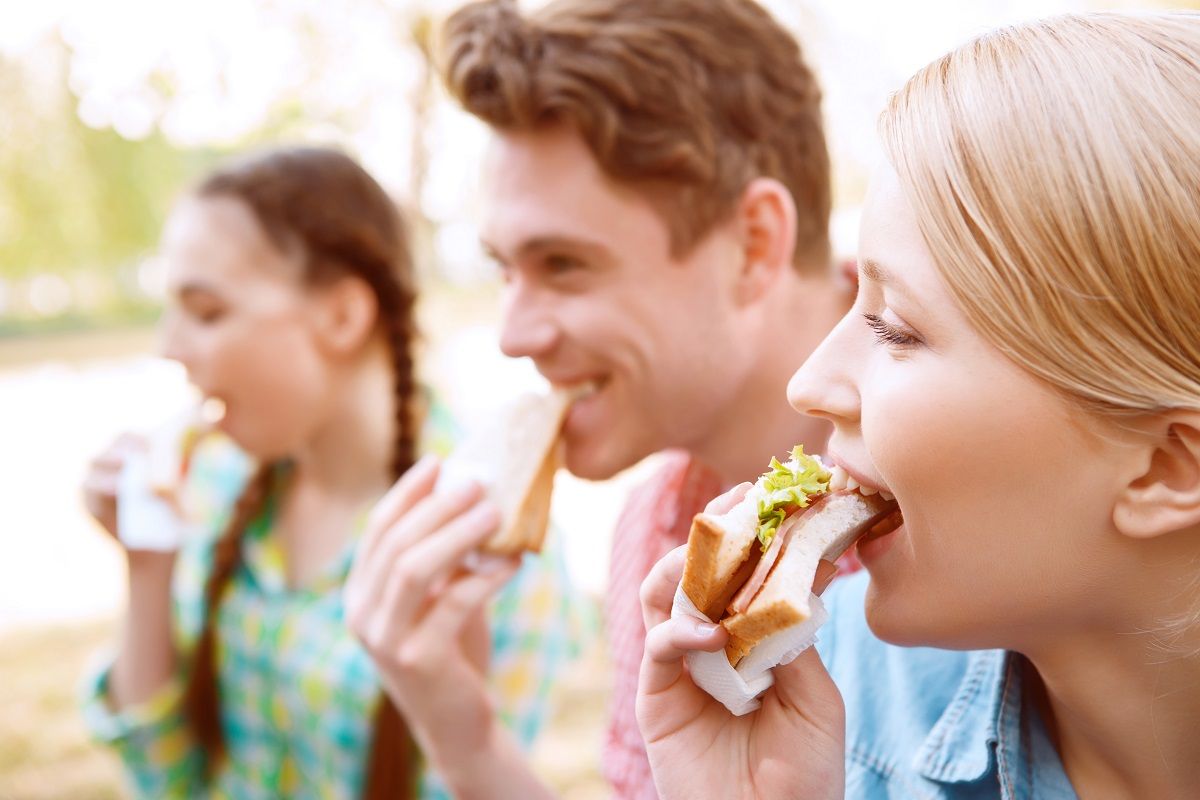 Young people eating sandwiches during picnic