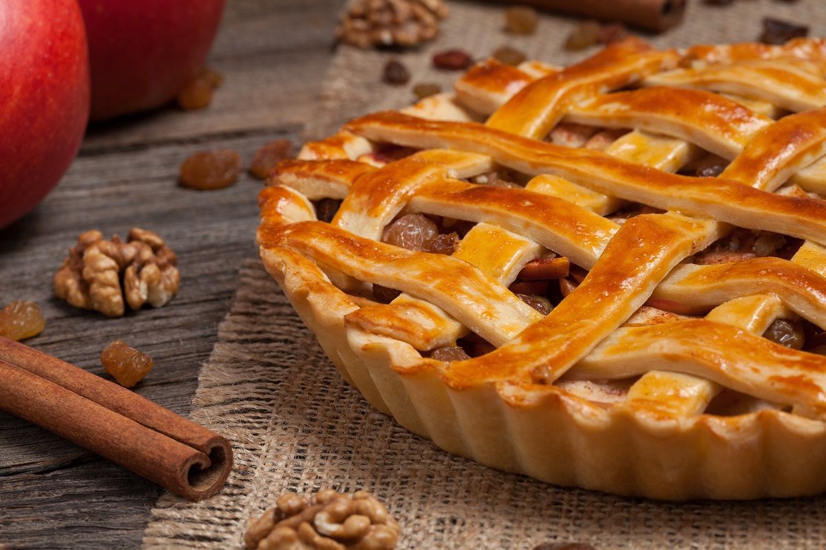 Apple pie with raisins and cinnamon on vintage wooden background