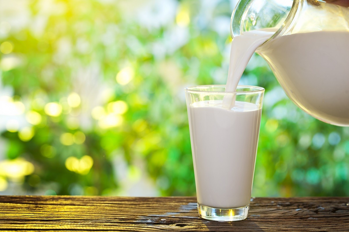 18958571 – pouring milk in the glass on the background of nature