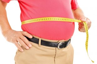 Fat mature man measuring his belly with measurement tape