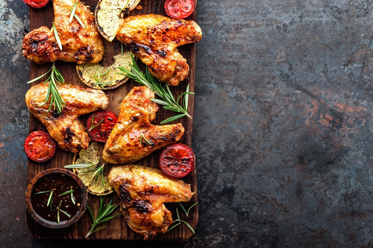 appetizing chicken wings grilled barbecue with spices and vegetables until crisp, top view, space for text