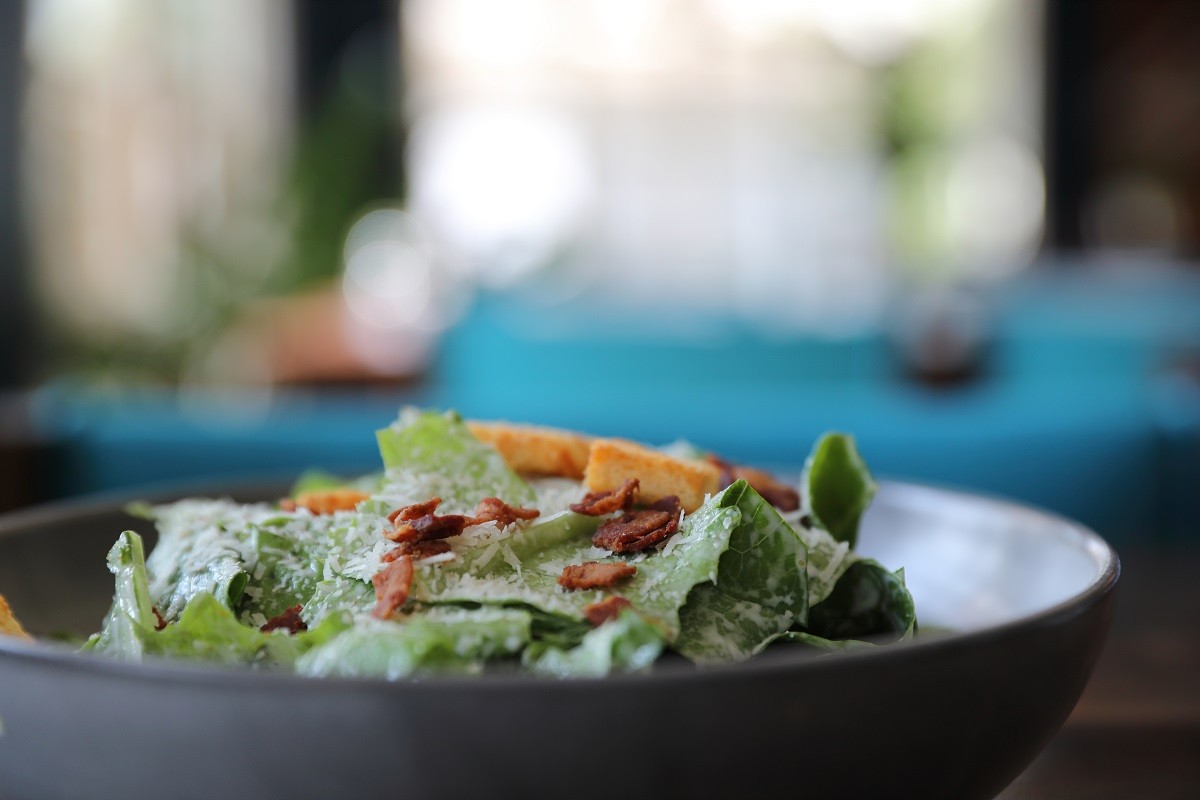 Caesar salad with crispy bread and bacon close up on wood backgr