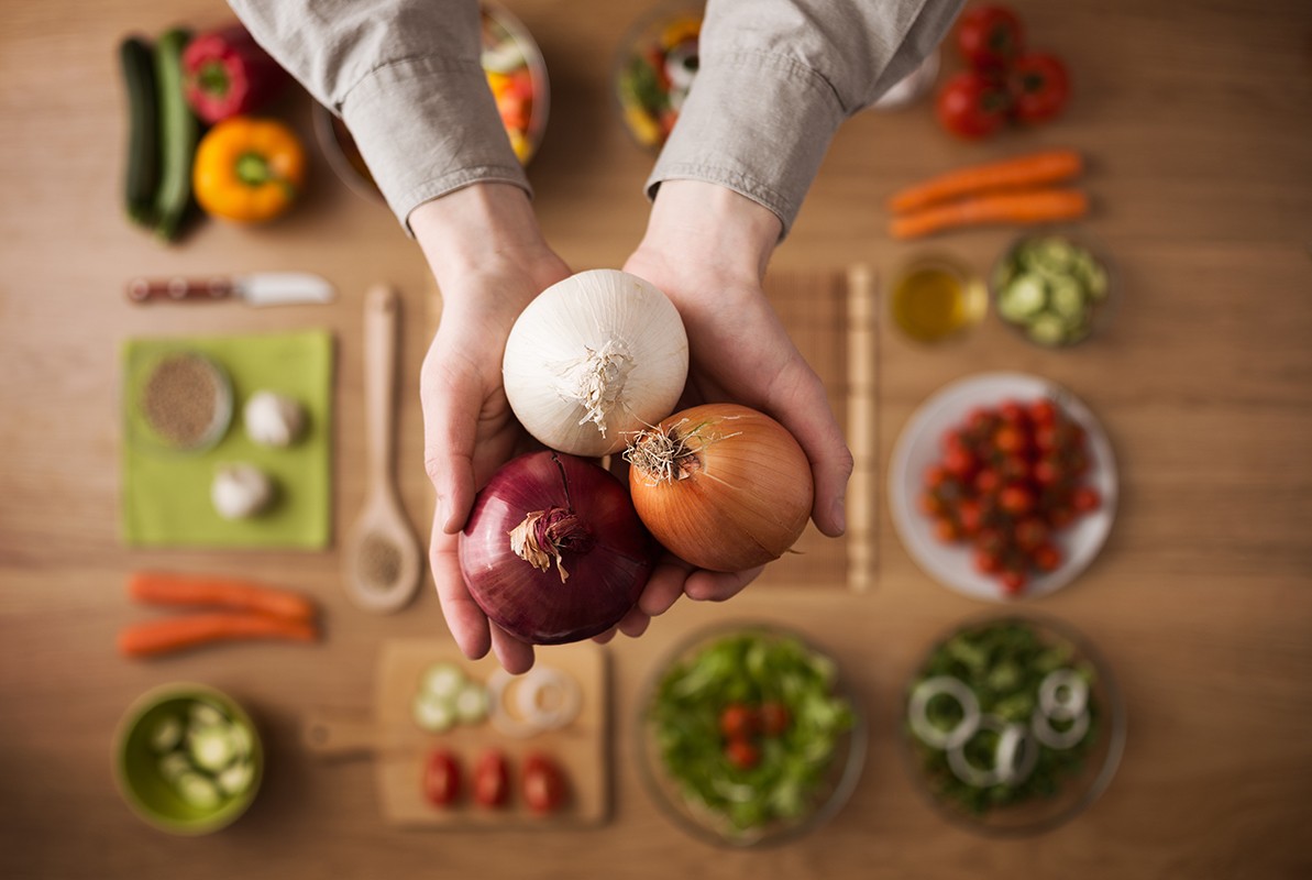 Hands holding different types of onions