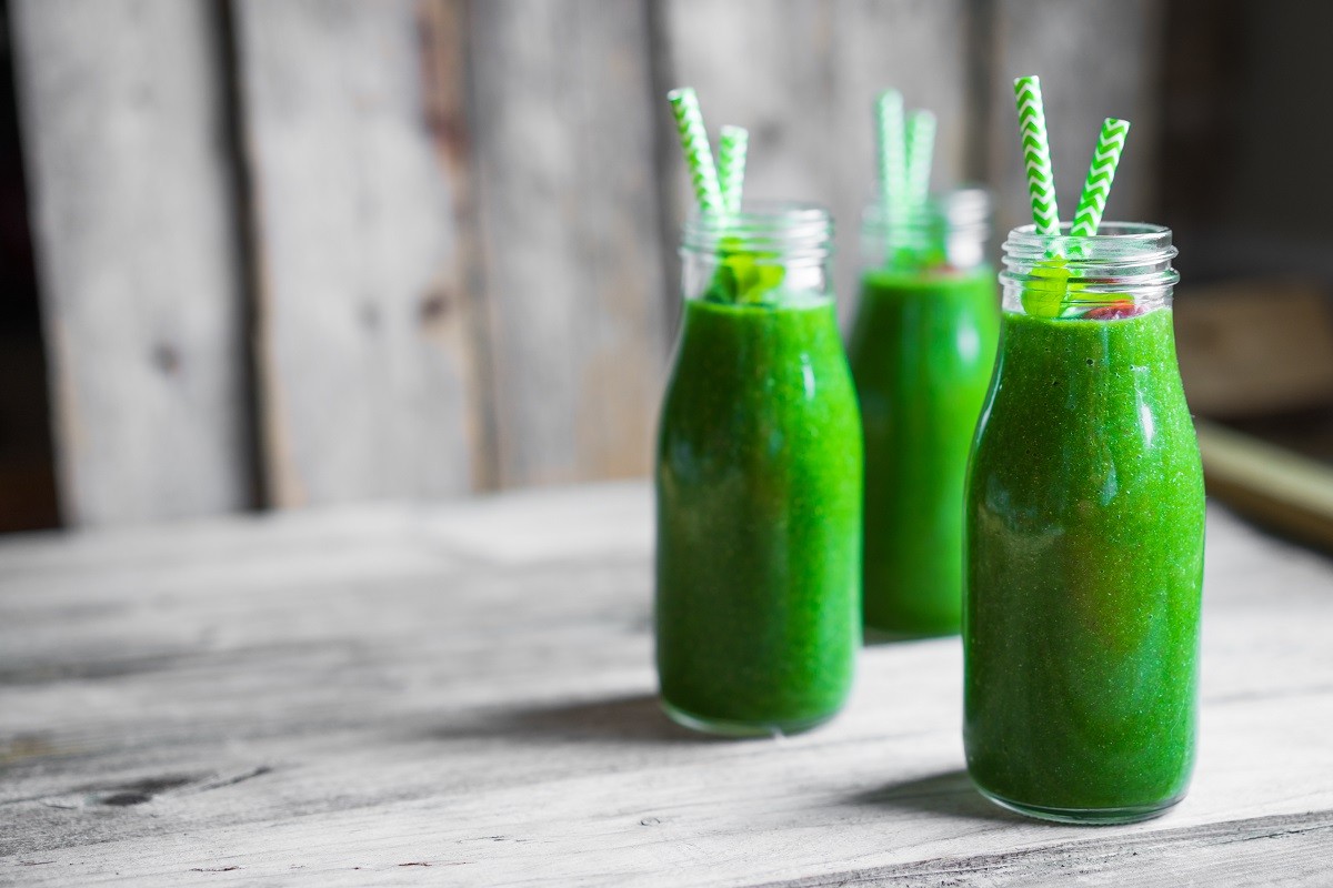 Fresh green smoothie on rustic wooden background