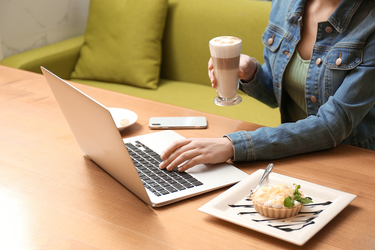 Blogger working with laptop in cafe, closeup