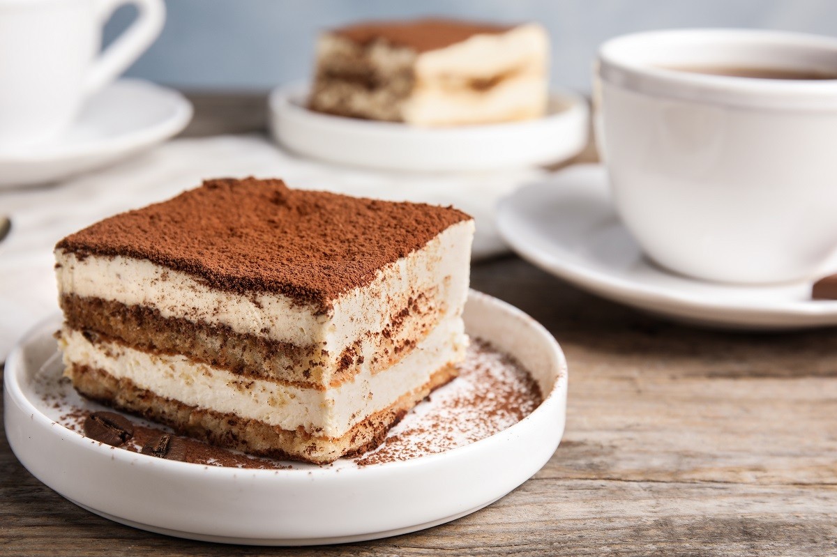 Composition with tiramisu cake and tea on table, closeup. Space for text