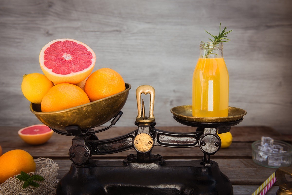 Fresh citrus fruits on the one scalepan of vintage weights and homemade juice on the other. Equivalent healthy value. Clean detox eating concept. Vegetarian, vegan, raw concept. Copy space.
