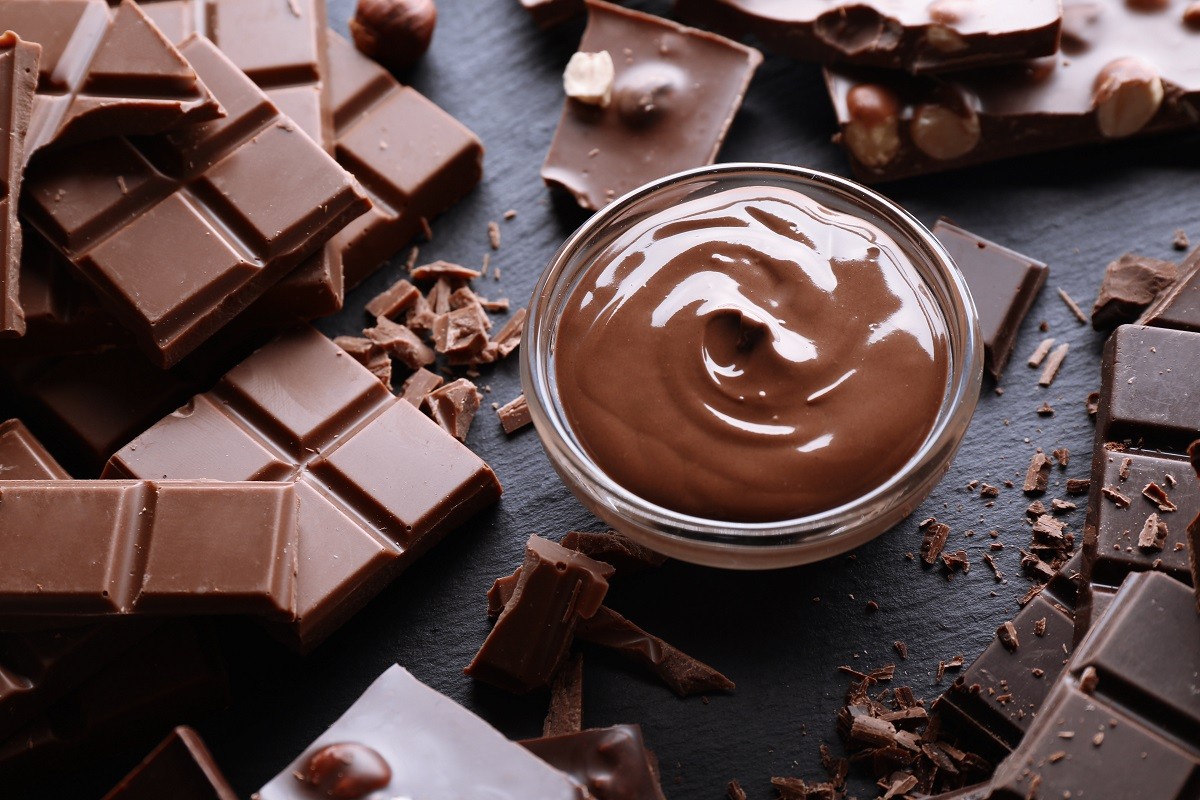 Bowl with melted chocolate and chopped bars, closeup