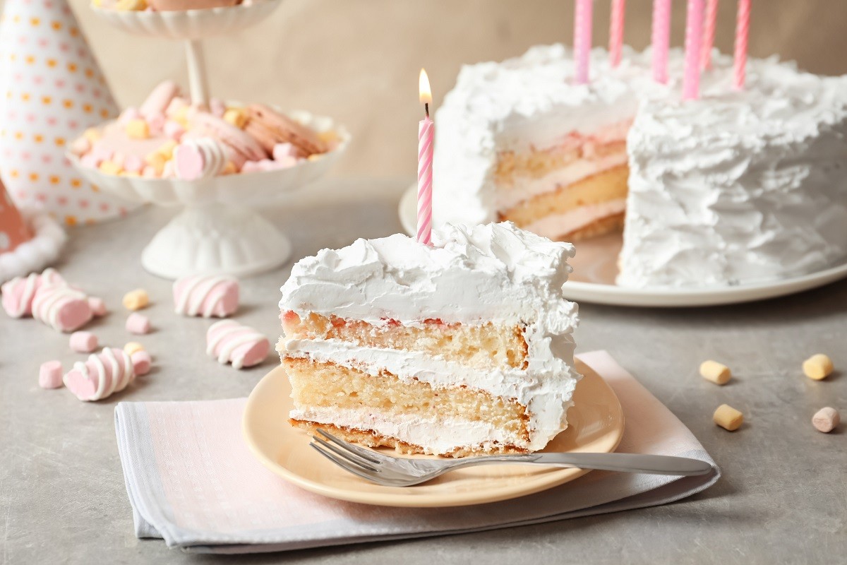 Piece of birthday cake with candle on table