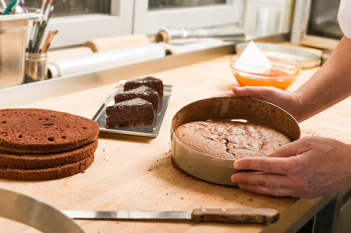 Cook taking out layer cake from cake form
