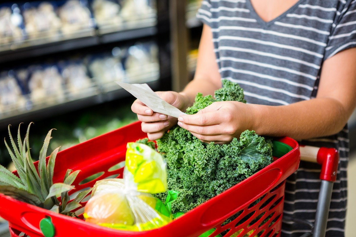 Woman with red basket holding list in supermarket