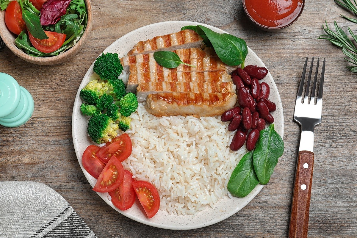 Tasty rice with beans served on wooden table, flat lay
