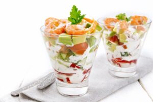 Salad with shrimp and avocado in two glasses on table