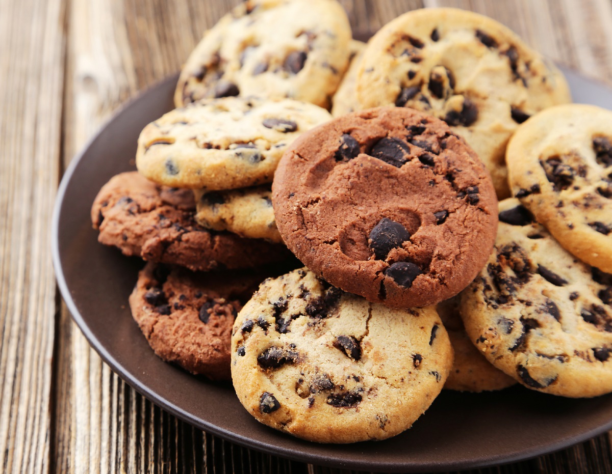 Chocolate chip cookies on plate on brown wooden background