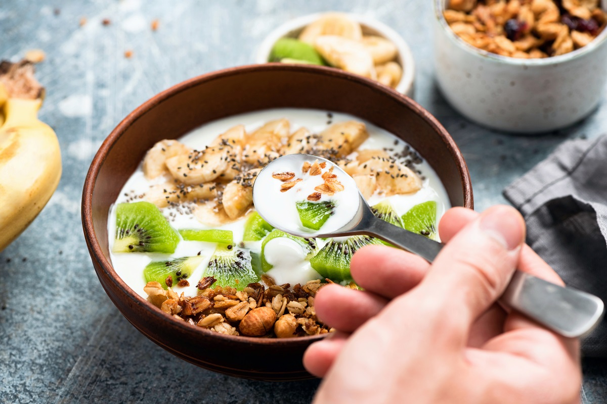 Granola,With,Yogurt,,Kiwi,And,Banana,In,Bowl.,Hand,With