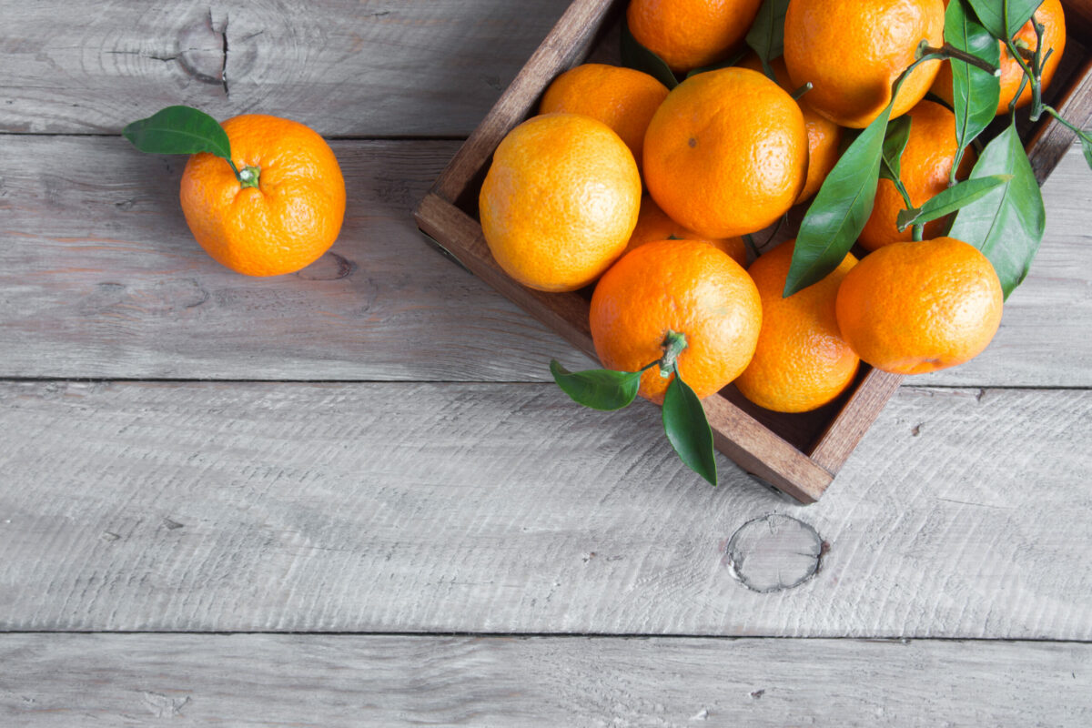 Tangerines,(oranges,,Clementines,,Citrus,Fruits),With,Green,Leaves,Over,Wooden