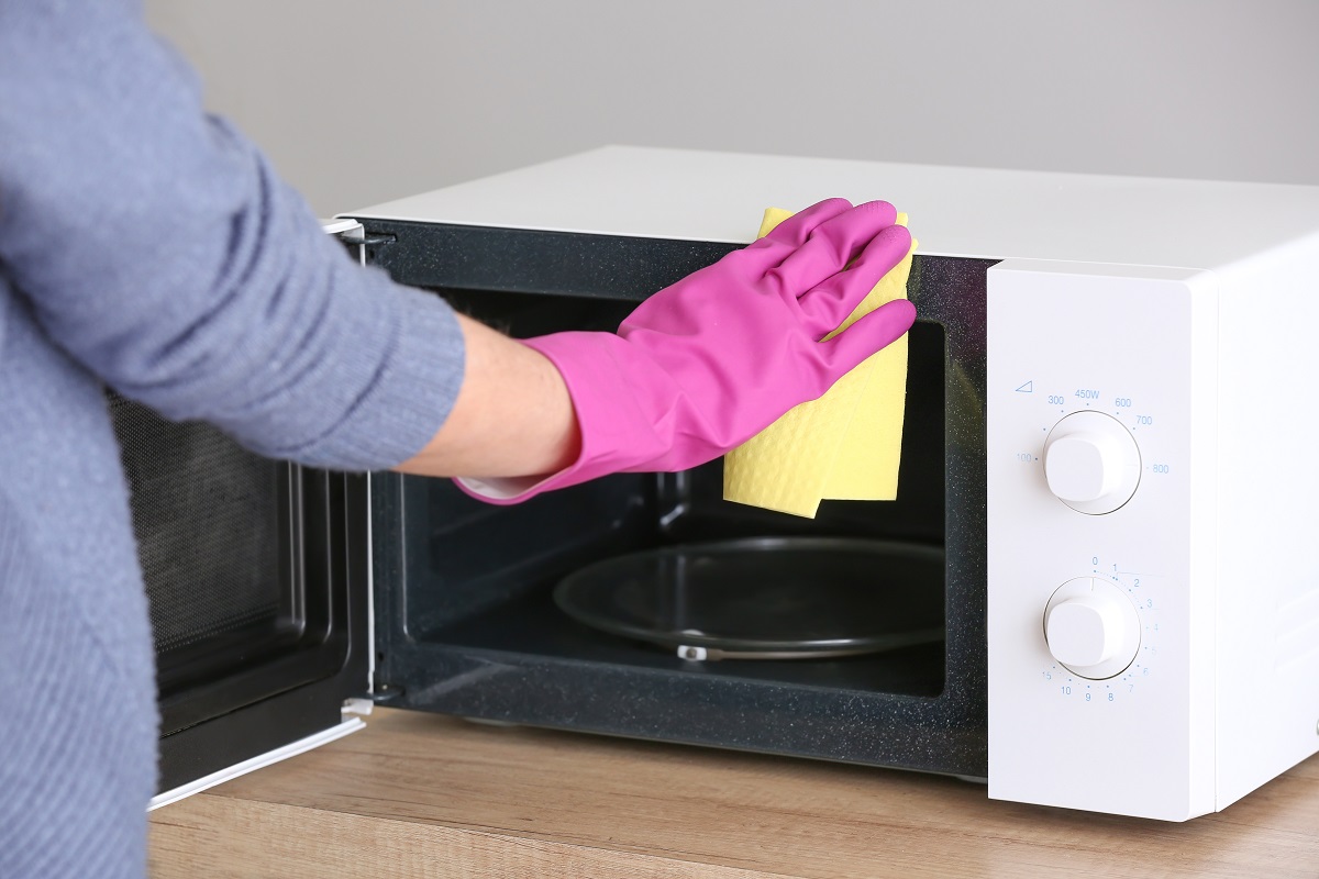 Woman,Cleaning,Microwave,Oven,In,Kitchen