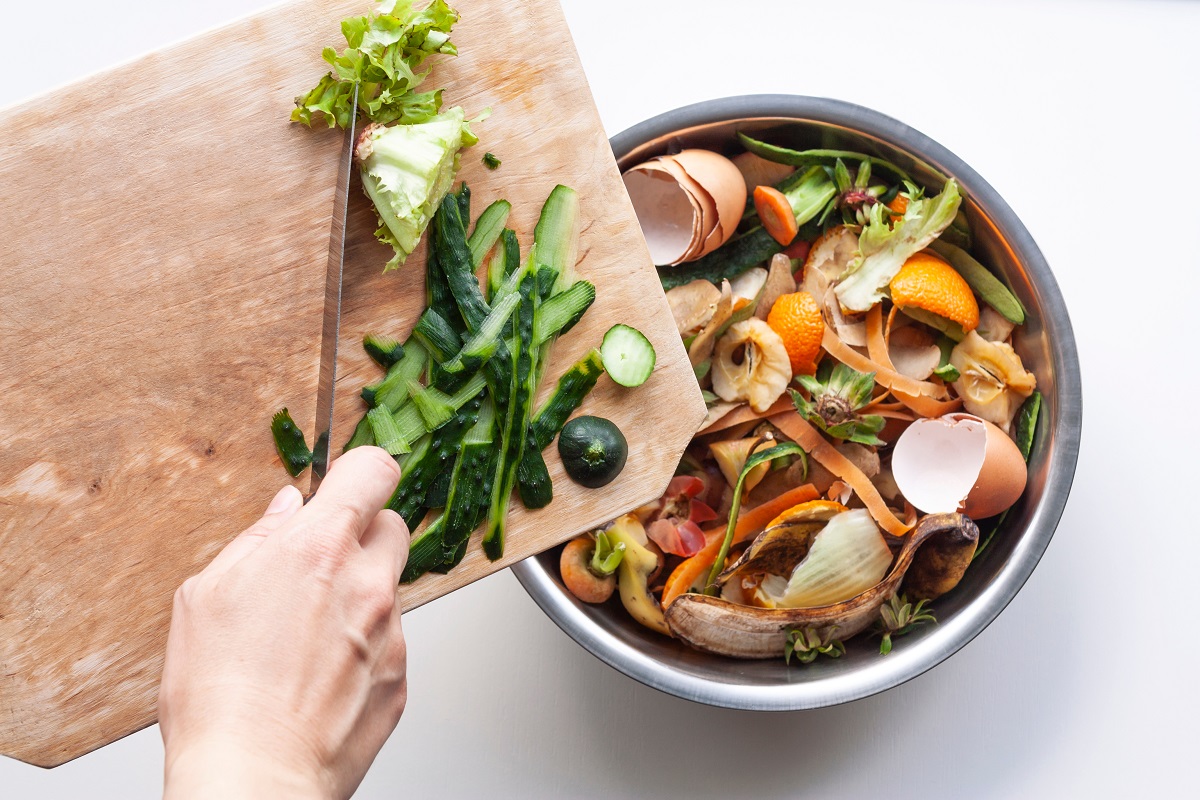 Vegetable,Peels,Are,Thrown,From,Cutting,Board,Into,An,Iron
