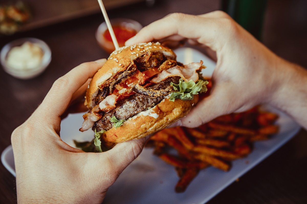 Man,Holds,Burger,With,Hands,And,Sweet,Potato,Fries,And