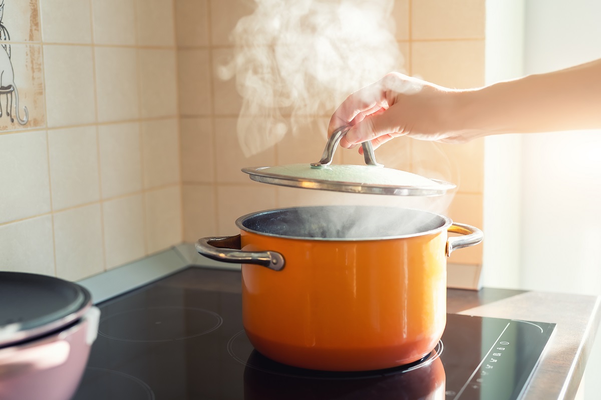 Female,Hand,Open,Lid,Of,Enamel,Steel,Cooking,Pan,On