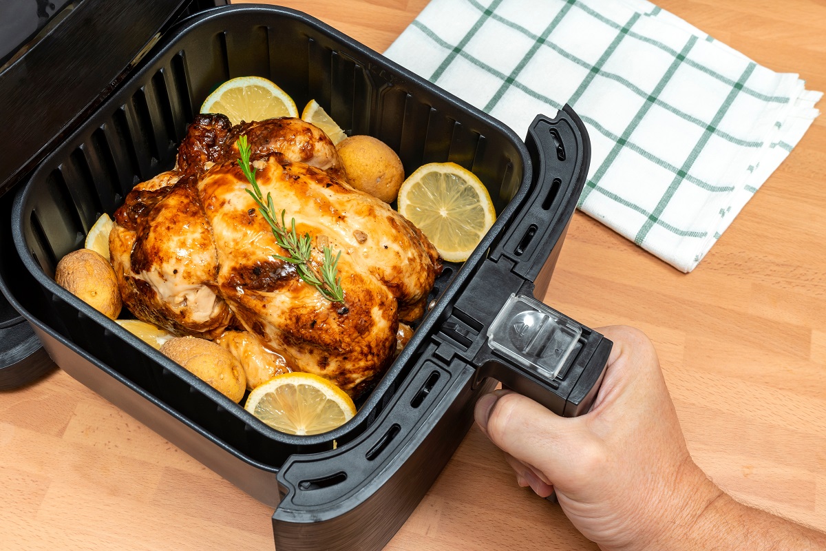 Hand,Cooking,Whole,Roasted,Chicken,With,Garnish,In,Air,Fryer