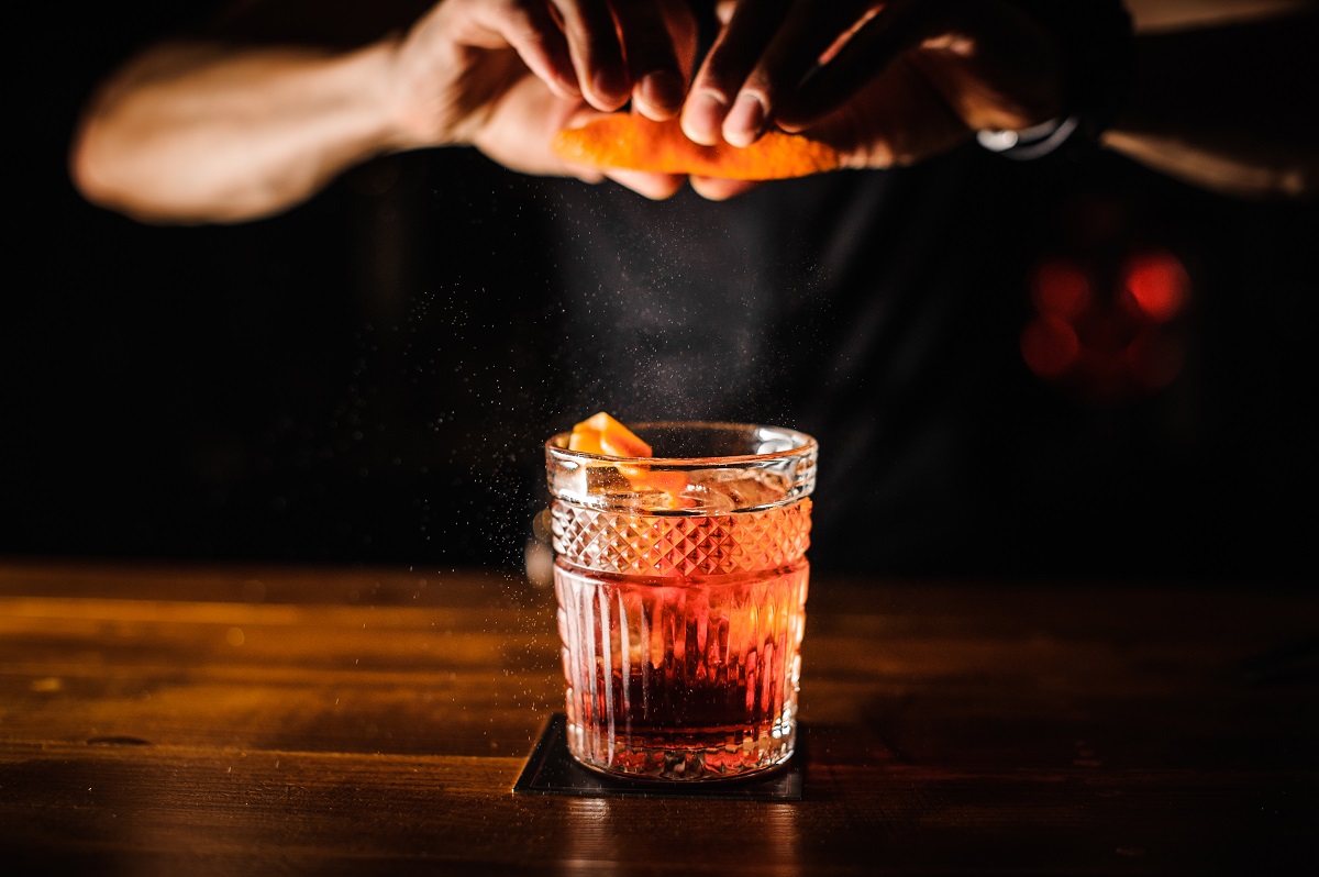 Bartender,With,Cocktail,And,Orange,Peel,Preparing,Cocktail,At,Bar.