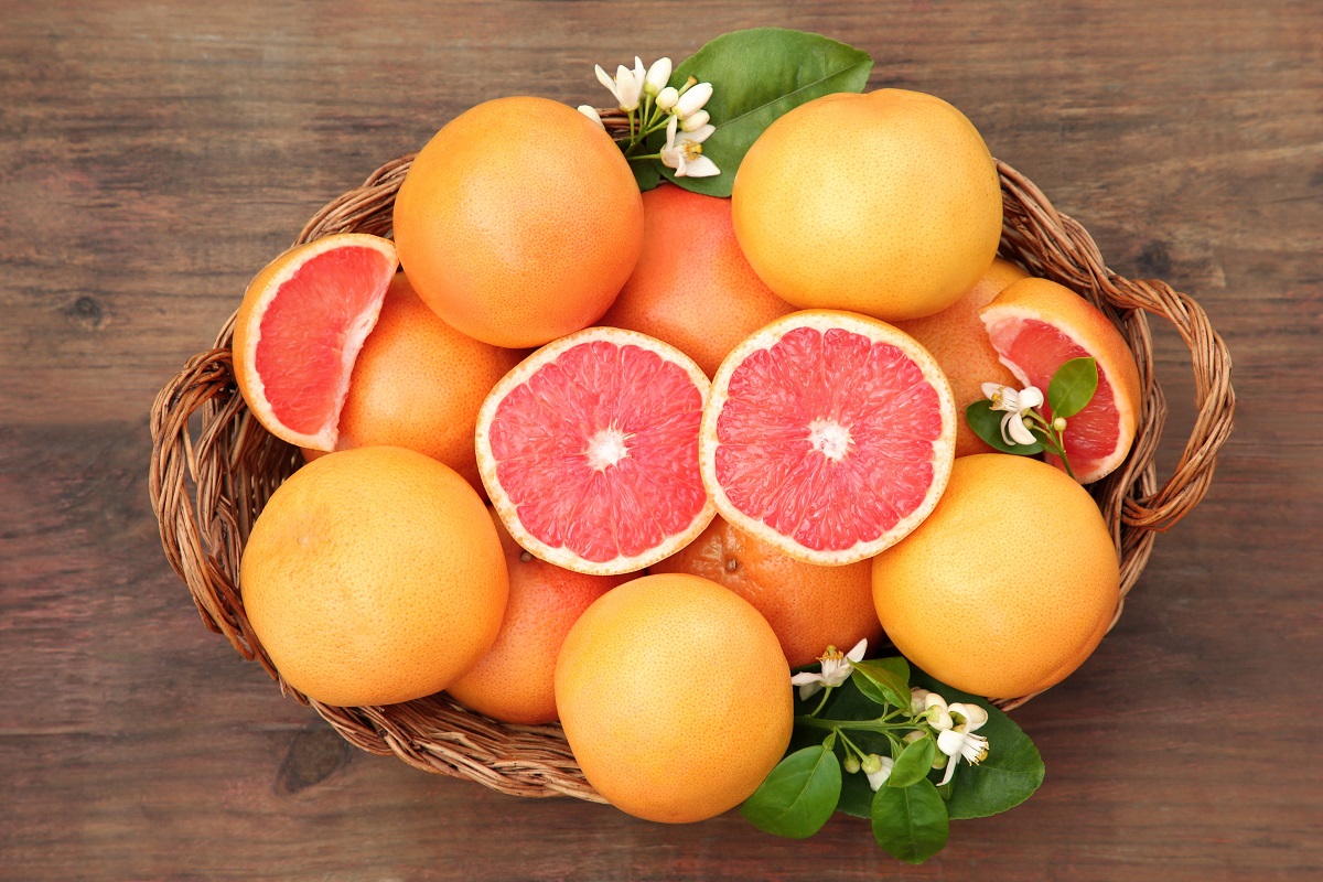 Wicker,Basket,With,Fresh,Grapefruits,And,Green,Leaves,On,Wooden