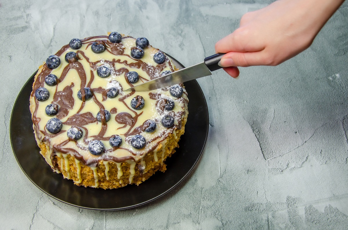 Woman’s,Hand,Cuts,A,Large,Homemade,Cake,With,A,Knife