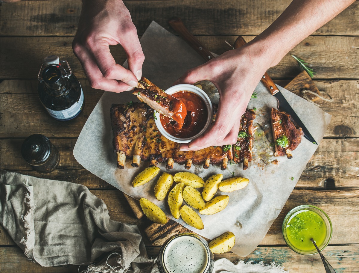 Man,Eating,Roasted,Pork,Ribs,With,Potato,Pieces,,Garlic,,Rosemary