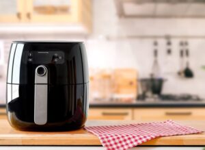 An,Electric,Air,Fryer,On,Table,With,Blurred,Kitchen,Background.