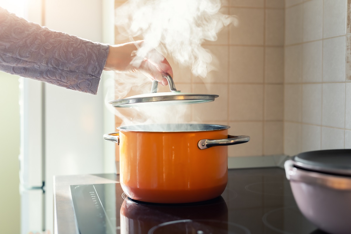 Female,Hand,Open,Lid,Of,Enamel,Steel,Cooking,Pan,On