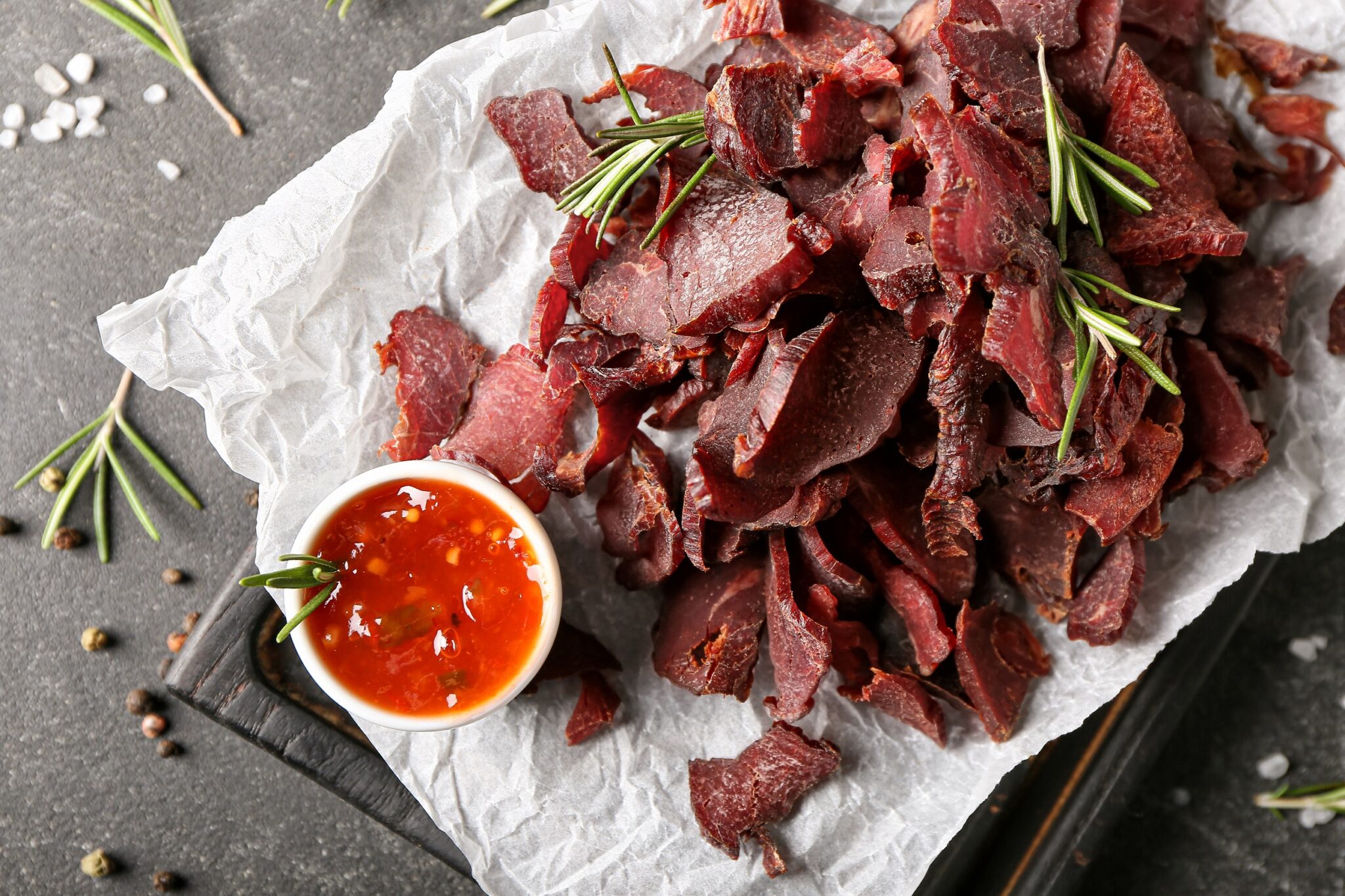 Board,With,Spicy,Beef,Jerky,And,Sauce,On,Dark,Background