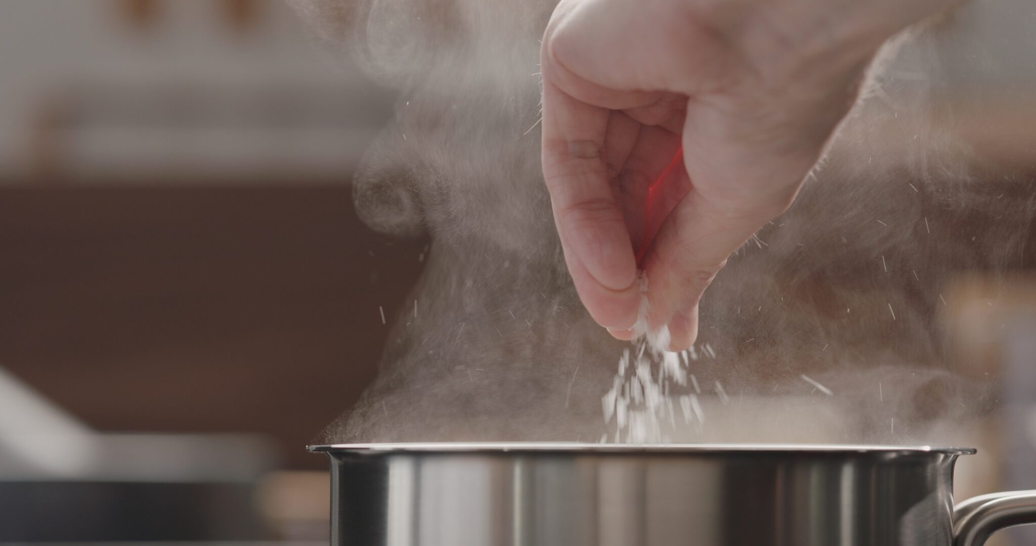 Man,Adding,Salt,To,Boiling,Water,In,Saucepan,,Wide,Photo