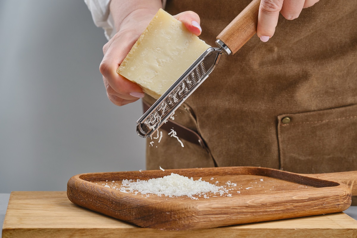 Hand,Of,A,Woman,Grating,Parmesan,Cheese,On,A,Gray