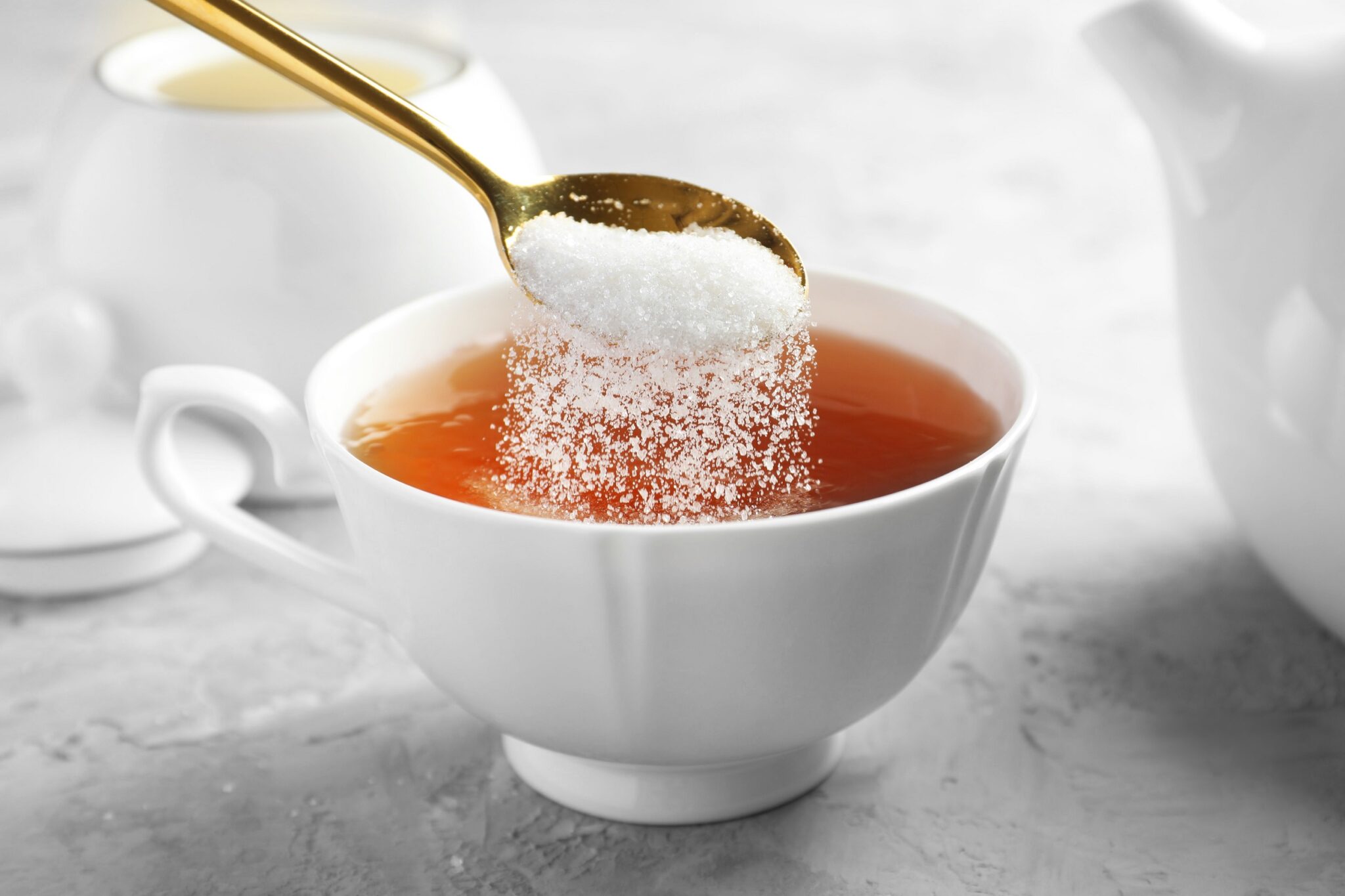 Adding,Sugar,Into,Cup,Of,Tea,At,Grey,Textured,Table,